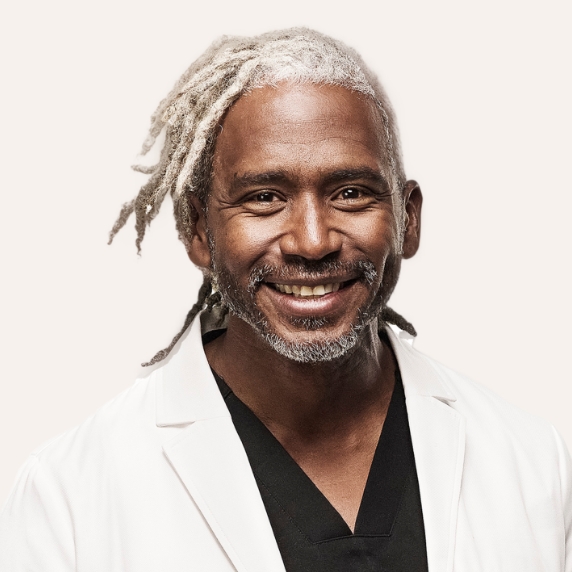 Male Heartland Supported Doctor in a white coat and dark scrubs
