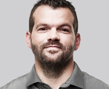 Confident male doctor with short hair wearing a pale grey collared shirt