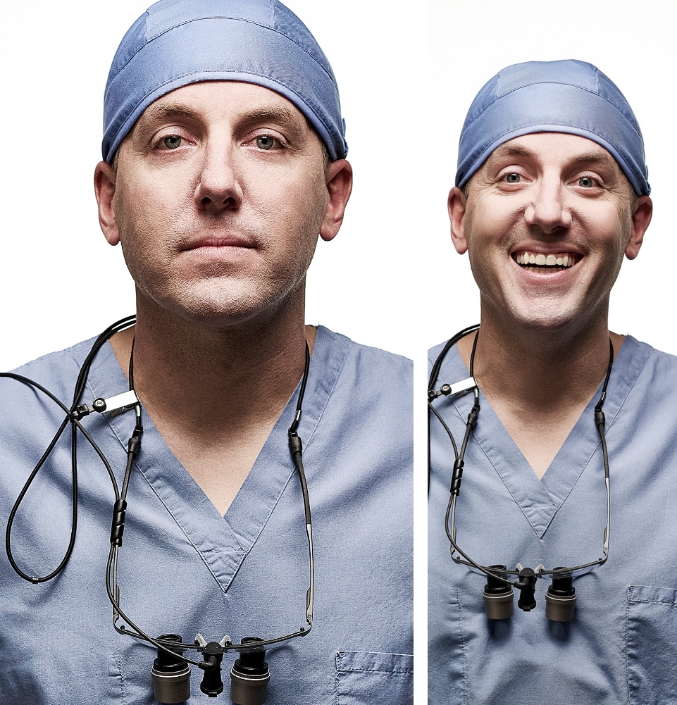 Male dentist in light blue scrubs with clinical glasses around his neck