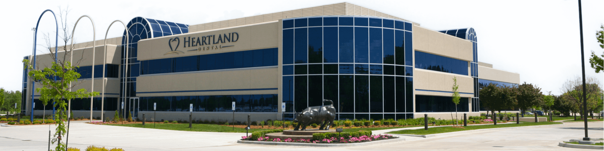 Corporate office building with beige stone exterior and blue windows with the Heartland Dental logo above the entrance