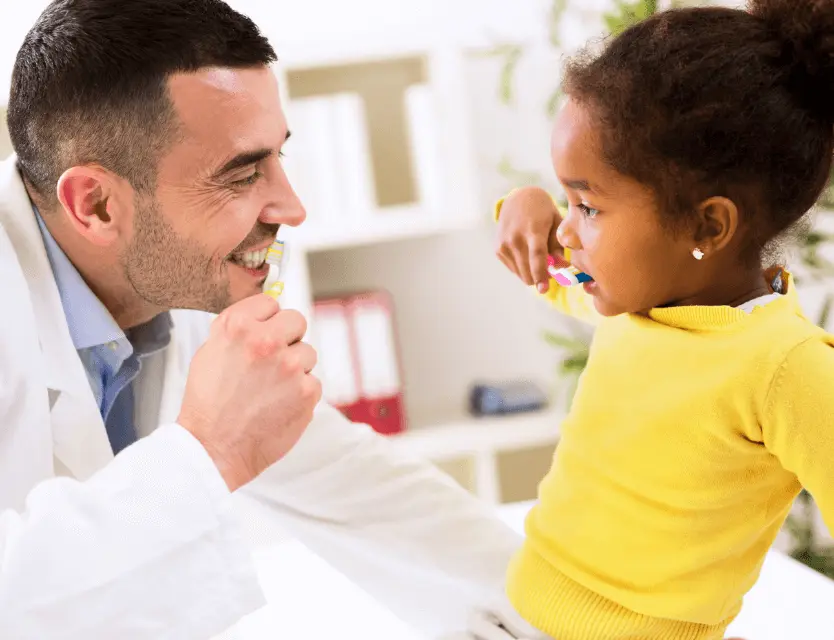 heartland doctor smiling at child brushing her teeth