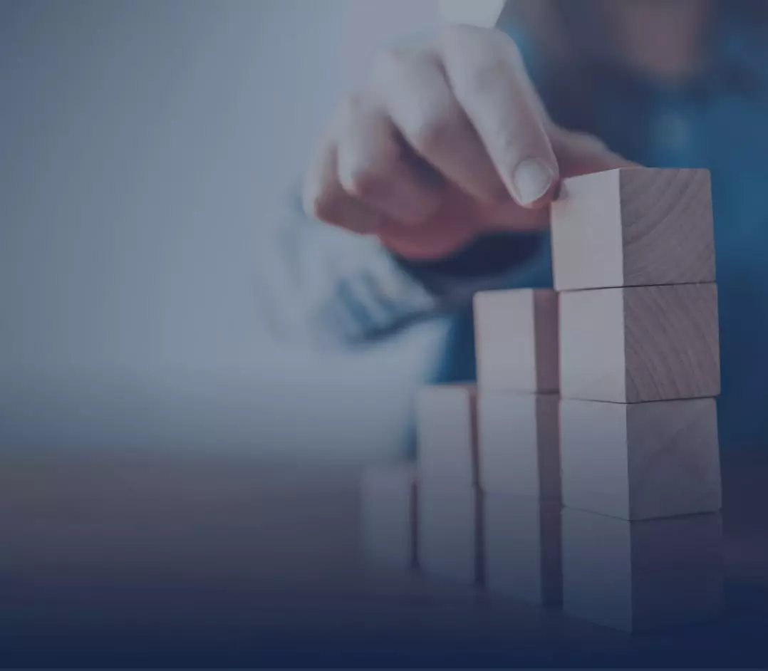 Closeup of a hand stacking 4 wooden blocks on a table